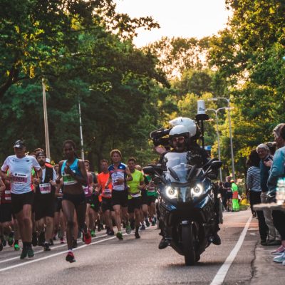 man riding touring motorcycle beside runners during daytime